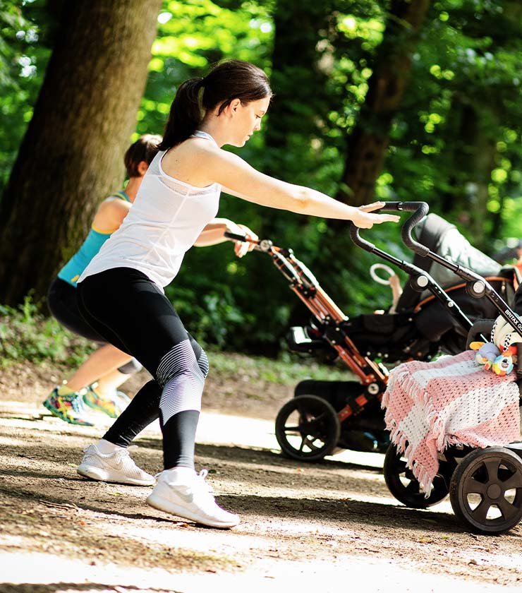 Frauen bei Dehnübungen am Kinderwagen bei "fit mit Baby - outdoor"